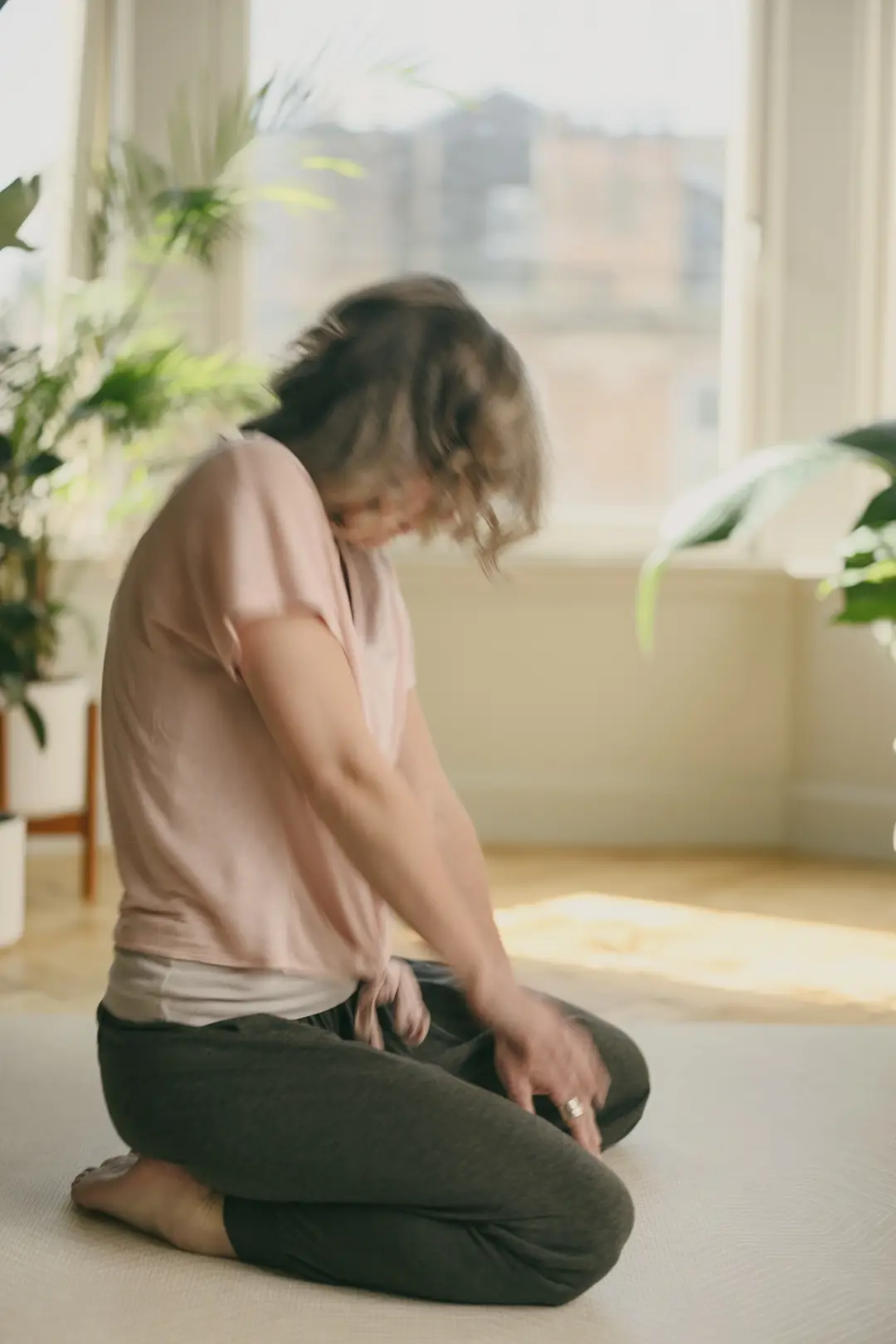 Nicki kneeling on a mat in a calm studio, eyes lowered