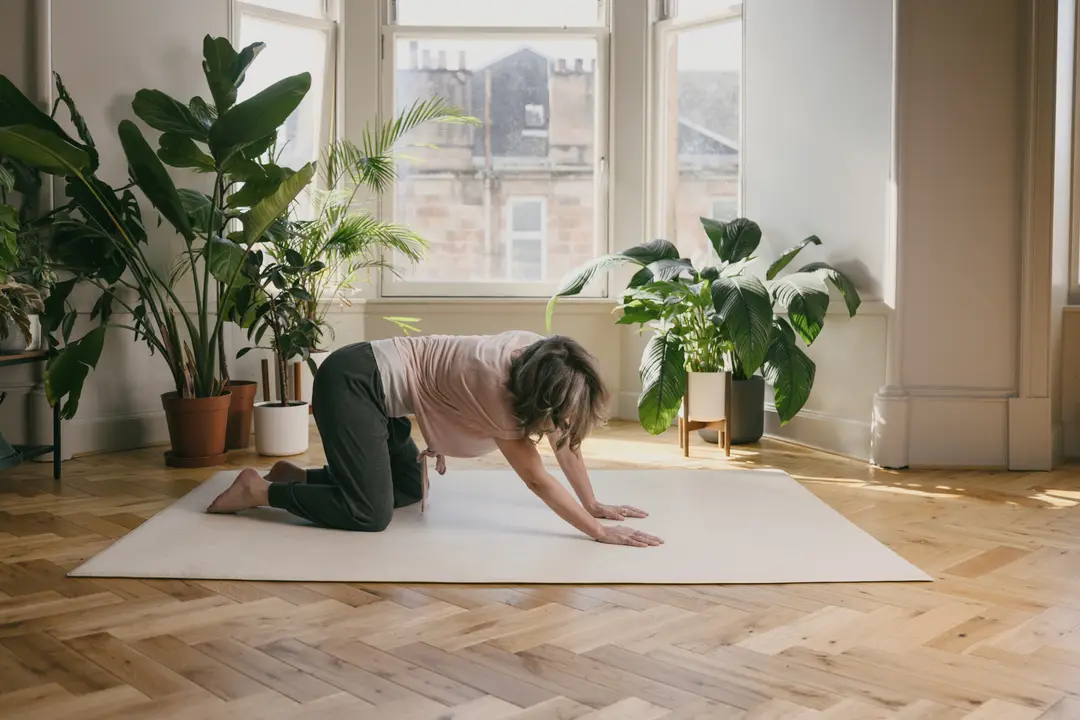 Nicki stretching on a mat in a calm, plant-filled studio